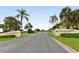 Inviting street view of Village Green Club Estates, lined with lush palm trees and well-maintained landscaping at 3278 Village Green Dr # 1024, Sarasota, FL 34239