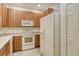 Well-lit kitchen featuring wood cabinets, white appliances, and tile flooring for a functional design at 3823 Parkridge Cir # 1-101, Sarasota, FL 34243