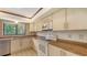 Functional kitchen with stainless steel dishwasher, white appliances, and a window overlooking lush greenery at 3837 Torrey Pines Blvd, Sarasota, FL 34238