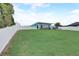Spacious backyard with lush green lawn, white fence, patio, and exterior view of the home, showcasing outdoor living at 408 Bryn Mawr Is, Bradenton, FL 34207