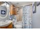 Cozy bathroom features a vanity, toilet, and shower with a blue seashell shower curtain; ample storage is provided with cabinet at 408 Bryn Mawr Is, Bradenton, FL 34207