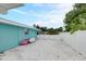 Exterior shot of the house showing a gravel parking area with fence, lush landscaping, and a bright blue exterior wall at 408 Bryn Mawr Is, Bradenton, FL 34207