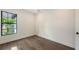 Bright bedroom features sleek hardwood floors, white walls, large window, and modern black door hardware at 428 Bocelli Dr, North Venice, FL 34275