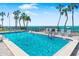 Community pool with inviting turquoise water, lounge chairs, palm trees, and ocean view at waterfront property at 4822 Ocean Blvd # 2D, Sarasota, FL 34242