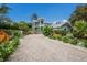 Charming two-story home boasts lush front yard landscaping, vibrant plants, and a brick driveway at 501 Reclinata Dr, Longboat Key, FL 34228