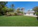 Well-manicured front lawn, mature trees, and lush landscaping of this charming two-story home at 501 Reclinata Dr, Longboat Key, FL 34228