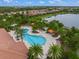 Aerial view of the large community pool and lounge area surrounded by palm trees near a lake at 5556 Cantucci St, Nokomis, FL 34275