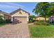 Charming single-story home with a well-manicured lawn and a brick driveway leading to an attached two-car garage at 5556 Cantucci St, Nokomis, FL 34275