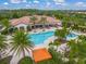 Aerial view of the community pool, featuring lounge chairs, palm trees, and orange sunshades at 5556 Cantucci St, Nokomis, FL 34275