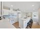 Well-lit kitchen with white cabinets, stainless appliances, quartz counters, breakfast bar, and light wood flooring at 6414 13Th Avenue W Dr, Bradenton, FL 34209