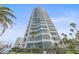 Modern high-rise condominium building with private balconies, palm trees and blue sky at 888 Blvd Of The Arts # 1008, Sarasota, FL 34236