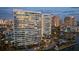 Stunning waterfront condominium with palm trees, lush landscaping, and resort-style amenities at dusk at 888 Blvd Of The Arts # 1008, Sarasota, FL 34236