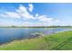 Lakeside view featuring a large lake surrounded by green grass, with a blue sky above at 10451 Ladybug Cv, Parrish, FL 34219