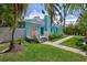 Charming home with a well-manicured lawn, palm trees and quaint walkway leading to a peach colored front door at 115 24Th W St, Bradenton, FL 34205