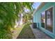 Featuring a well-maintained side yard with lush greenery and a stone pathway beside the colorful house at 115 24Th W St, Bradenton, FL 34205