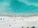 Aerial beach view of turquoise waters and sandy shore with scattered umbrellas and beachgoers at 17136 Blowfish Dr, Nokomis, FL 34275