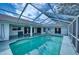 Screened-in pool with clear blue water, surrounded by a spacious patio and white exterior walls at 18576 Alphonse Cir, Port Charlotte, FL 33948