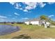 Backyard with a serene pond view, lush green lawn, and white exterior elevation at 3831 Creekside Park Dr, Parrish, FL 34219