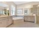 Bright bathroom featuring double sinks, a soaking tub, decorative art, and a glass-enclosed shower at 3831 Creekside Park Dr, Parrish, FL 34219