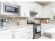 Kitchen boasts stainless steel appliances, white cabinets, gray backsplash, and granite countertops at 9978 Bright Water Drive, Englewood, FL 34223
