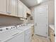 A tidy laundry room with white washer and dryer, cabinets, sink, and neutral wall colors at 16741 Ellsworth Ave, Bradenton, FL 34202