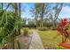 Beautiful backyard featuring gravel path, manicured grass, and mature landscaping at 28 Tall Trees Ct, Sarasota, FL 34232