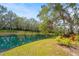 A peaceful backyard view showcases a tranquil pond with lush greenery and vibrant landscaping at 28 Tall Trees Ct, Sarasota, FL 34232