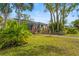 Exterior view of the home with a screened lanai, tropical landscaping, and gravel path at 28 Tall Trees Ct, Sarasota, FL 34232