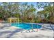 Community pool with surrounding mature trees, picnic shelter and sun loungers at 28 Tall Trees Ct, Sarasota, FL 34232