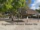 Outdoor view of the Englewood Farmer's Market site with sandy ground, trees and an open thatched roof structure at 470 Leach St, Englewood, FL 34223
