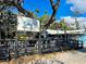The Blue Pineapple Bistro features shaded outdoor seating with tables and benches under a large, leafy tree at 470 Leach St, Englewood, FL 34223