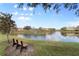 Community pond with a bench along the grassy shoreline and neighborhood homes in the background at 5435 Soapstone Place # 22-103, Sarasota, FL 34233