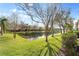 Community pond with a grassy shoreline, mature trees, and neighborhood homes in the background at 5435 Soapstone Place # 22-103, Sarasota, FL 34233