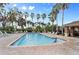 Community pool featuring a pool, lounge chairs, tables, and palm trees on a sunny day at 5435 Soapstone Place # 22-103, Sarasota, FL 34233