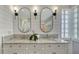 Bathroom featuring granite-topped dual sinks, framed mirrors, and decorative glass block window at 619 Buttonwood Dr, Longboat Key, FL 34228