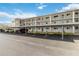 Exterior of building showing the parking area, staircases, black metal railings, and well-maintained landscaping at 649 S Tamiami Trl # 210, Venice, FL 34285