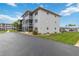 Condo building exterior features screened balconies, paved driveway, and well-maintained landscaping at 649 S Tamiami Trl # 210, Venice, FL 34285