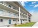 Exterior of building with blue doors, black metal railings, well maintained lawn, and an American flag at 649 S Tamiami Trl # 210, Venice, FL 34285