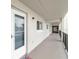 Hallway with the unit's front door, exterior light fixture, and a grey painted floor at 649 S Tamiami Trl # 210, Venice, FL 34285