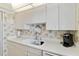 Compact kitchen features white cabinets, white countertop, and tiled floor at 649 S Tamiami Trl # 210, Venice, FL 34285