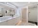 Bright bathroom featuring a double vanity, marble countertops, and glass-enclosed shower at 650 Golden Gate Pt # 403, Sarasota, FL 34236