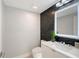 Modern bathroom featuring black tile, sleek vanity with white countertop, and a decorative mirror at 650 Golden Gate Pt # 403, Sarasota, FL 34236