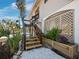 Detailed view of the wooden staircase leading to the front door, accented by vibrant tropical foliage and greenery at 650 Penfield St, Longboat Key, FL 34228