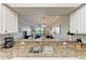 Modern kitchen featuring granite countertops, stainless steel sink, and a view into the living room at 7019 River Hammock Dr # 104, Bradenton, FL 34212