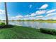 A serene pond view shows lush grass leading to still water, under a blue, partly cloudy sky at 7019 River Hammock Dr # 104, Bradenton, FL 34212