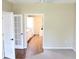 Bright, spacious bedroom with light tan walls, wood floors, and white french doors to a bathroom and hallway at 7340 Golf Pointe Cir, Sarasota, FL 34243