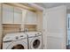 Bright laundry room with overhead storage and a modern, front-loading washer and dryer at 7340 Golf Pointe Cir, Sarasota, FL 34243