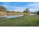 Scenic view of a tranquil pond surrounded by lush green grass, mature trees, and clear blue skies at 7340 Golf Pointe Cir, Sarasota, FL 34243