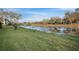 Scenic view of a tranquil pond surrounded by lush green grass, mature trees, and clear blue skies at 7340 Golf Pointe Cir, Sarasota, FL 34243