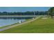 Picturesque waterfront path with numbered markers, lush green grass, and the calm lake reflecting the sky at 7632 Plantation Cir, Bradenton, FL 34201